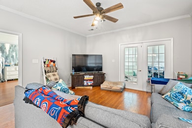 Living room featuring hardwood / wood-style flooring, crown molding, and ceiling fan