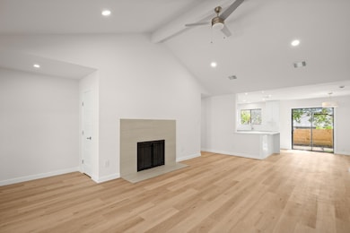 Unfurnished living room with recessed lighting, beam ceiling, a fireplace with flush hearth, light wood-style floors, and high vaulted ceiling