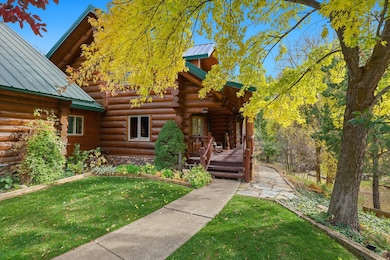 Doorway to property with log exterior, a metal roof, and a yard
