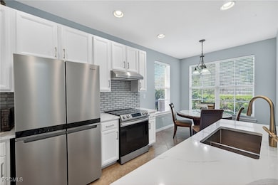 Kitchen featuring stainless steel appliances, decorative backsplash, pendant lighting, white cabinets, and recessed lighting