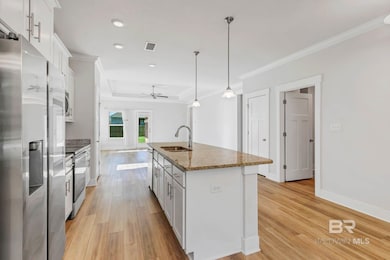 Kitchen featuring stainless steel appliances, white cabinetry, hanging light fixtures, an island with sink, and recessed lighting