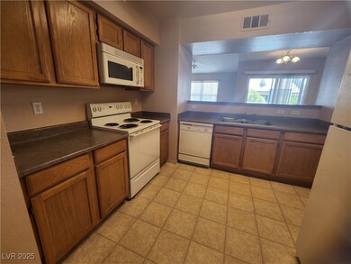 Kitchen with white appliances, dark countertops, brown cabinets, and a chandelier