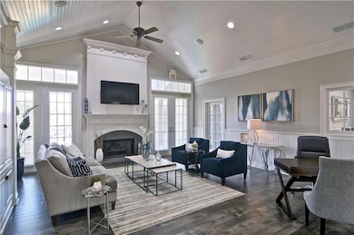 Living room featuring french doors, high vaulted ceiling, dark wood-type flooring, ceiling fan, and ornamental molding