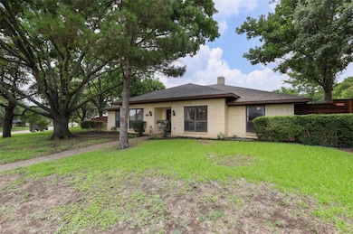 Ranch-style home featuring brick siding, a front lawn, a chimney, and roof with shingles