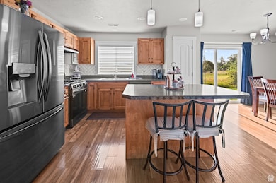 Kitchen with appliances with stainless steel finishes, a breakfast bar area, decorative backsplash, dark countertops, and decorative light fixtures