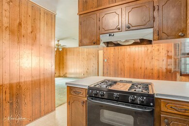 Kitchen featuring wood walls, ceiling fan, and bla