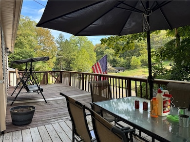 Deck with outdoor dining area and view of wooded area