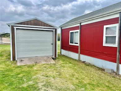 View of home's exterior with an outbuilding, a yard, and a shingled roof