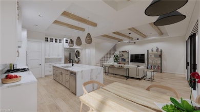 Kitchen with a kitchen island with sink, white cabinets, sink, light wood-type flooring, and appliances with stainless steel finishes