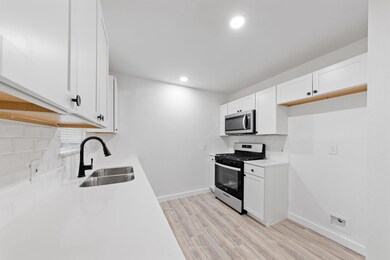 Kitchen with sink, white cabinetry, appliances wit