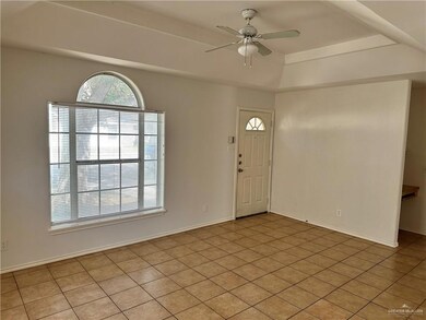 Foyer with ceiling fan, a raised ceiling, and light tile patterned flooring