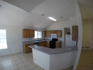 Kitchen featuring sink, kitchen peninsula, vaulted ceiling, white appliances, and light tile patterned floors