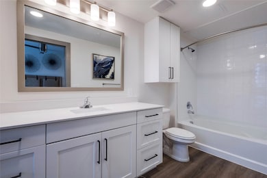 Full bathroom featuring dark wood finished floors, vanity, bathtub / shower combination, and recessed lighting