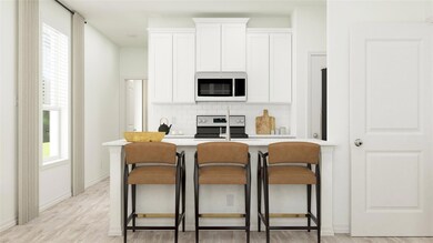 Kitchen with white microwave, white cabinetry, a k
