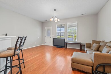 Living area with light wood-type flooring, a chandelier, a textured ceiling, and baseboards
