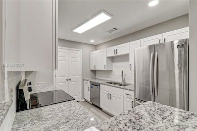 Kitchen featuring white cabinetry, backsplash, sta