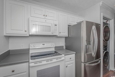 Kitchen with white cabinetry, stacked washer / dry