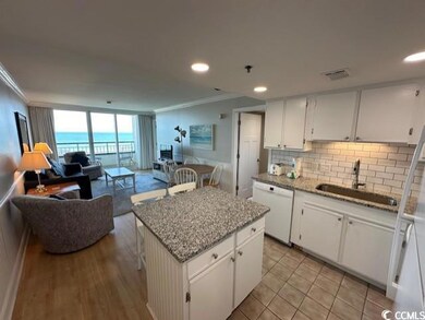 Kitchen featuring white dishwasher, a kitchen island, and white cabinets