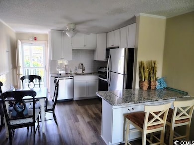 Kitchen with appliances with stainless steel finishes, a textured ceiling, a peninsula, dark wood-style flooring, and ceiling fan. All appliances convey.