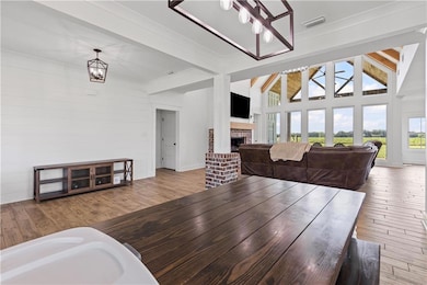 Dining room featuring a chandelier, light wood-type flooring, a fireplace, beam ceiling, and a towering ceiling