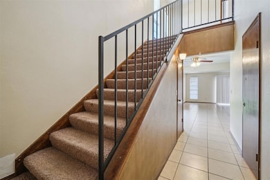 Stairway with a ceiling fan, baseboards, tile patt