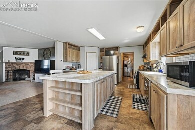 Kitchen featuring open shelves, appliances with stainless steel finishes, light countertops, a kitchen island, and a sink