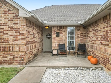 Entrance to property featuring brick siding and a shingled roof