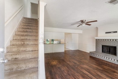 Stairway with wood finished floors, a textured ceiling, a fireplace, and a ceiling fan