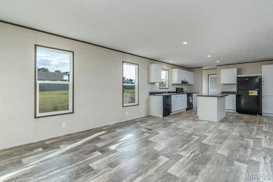 Kitchen with black appliances, light wood-style floors, white cabinetry, dark countertops, and recessed lighting