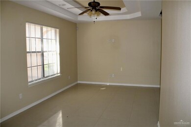 Spare room with a tray ceiling, ceiling fan, and light tile patterned flooring