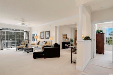Living room with light colored carpet, ornamental molding, a ceiling fan, and ornate columns
