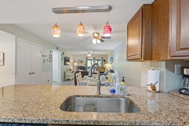 Kitchen with brown cabinets, a ceiling fan, open floor plan, and a sink