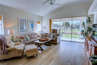 Living room featuring ceiling fan, plenty of natural light, lofted ceiling, and light wood-type flooring