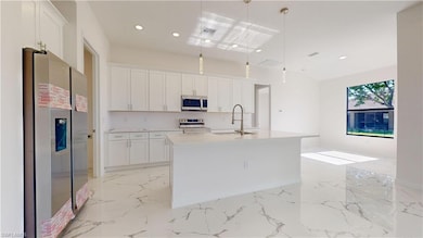 Kitchen featuring appliances with stainless steel finishes, a sink, white cabinetry, and recessed lighting