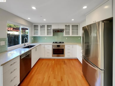 Kitchen featuring stainless steel appliances, white cabinets, backsplash, light stone counters, and recessed lighting