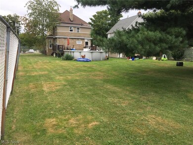 View of back of home with large deck, 8' chain link fence and huge back yard