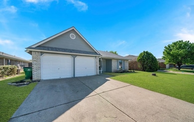 Single story home featuring a front yard, driveway, a garage, a shingled roof, and brick siding