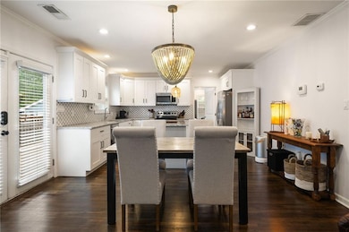 Dining area featuring a chandelier, crown molding, dark wood-style floors, and recessed lighting