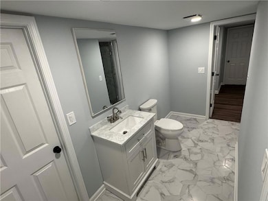Half bathroom with marble look tile flooring, baseboards, and vanity