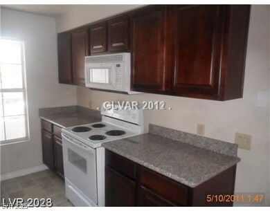 Kitchen with white appliances, baseboards, and dar