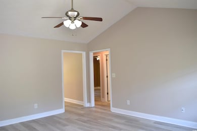 Empty room with ceiling fan, light wood finished floors, high vaulted ceiling, and baseboards