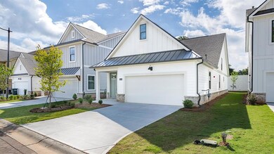 Modern inspired farmhouse with a standing seam roof, board and batten siding, concrete driveway, and a shingled roof