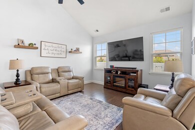 Living area with dark wood-type flooring, ceiling fan, and vaulted ceiling