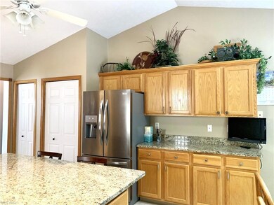 Kitchen featuring stainless steel refrigerator with ice dispenser, light stone countertops, brown cabinets, and lofted ceiling
