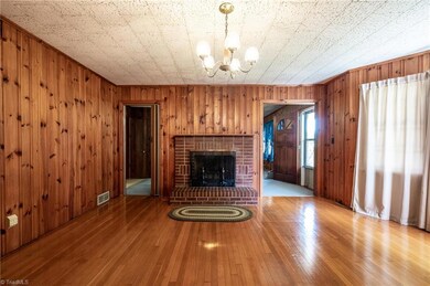 Dining room features lovely hardwood floors, wood paneled walls, bay window and wood burning fireplace.