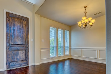 Foyer featuring dark wood-style floors, a chandelier, and a decorative wall