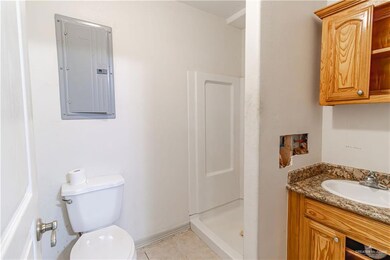Bathroom featuring walk in shower, vanity, tile patterned flooring, toilet, and electric panel