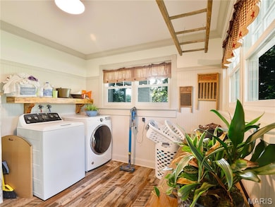 Laundry room with wood finished floors, separate washer and dryer, wainscoting, and crown molding