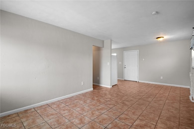 Unfurnished room with light tile patterned flooring and baseboards
