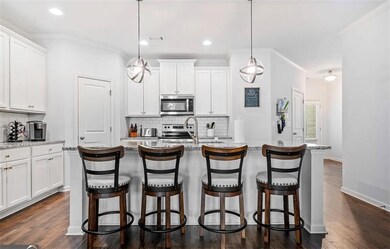 Kitchen featuring stainless steel appliances, backsplash, a kitchen bar, dark wood-style flooring, and white cabinets